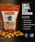 A bag of Bourbon Pistachios with text on the right reading 'Sweet Smoke, Bold Bourbon' and product benefits, set on a dark wood background with loose pistachios in front.
