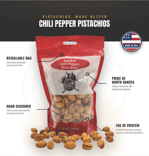 A 12 oz resealable bag of Smoked Chili Pepper Pistachios by The Pine Ridge Creamery, shown on a white and black graphic background with callout text highlighting features like resealable bag, hand seasoned, and pride of North Dakota. Several whole pistachios are scattered in front of the bag.