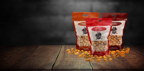 Three packages of smoked pistachios on a wooden surface with a dark background