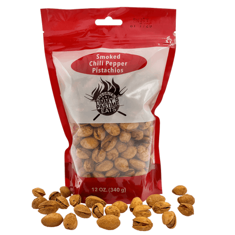 Red package of smoked chili pepper pistachios with pistachios scattered around on a white background